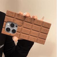 Thumbnail for A person holding a chocolate-colored silicone iPhone case featuring Rilakkuma and Hello Kitty characters.