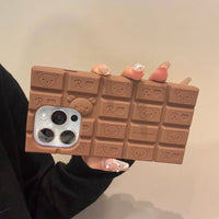 Thumbnail for A person holding a chocolate-colored silicone iPhone case featuring Rilakkuma and Hello Kitty characters.